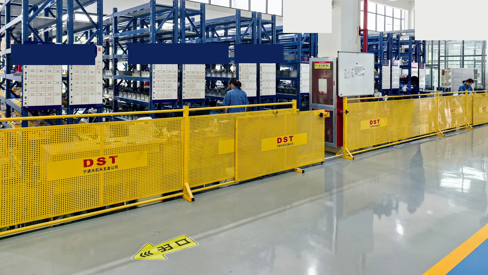 Organized fastener warehouse racks behind DST safety barriers in a production plant aisle